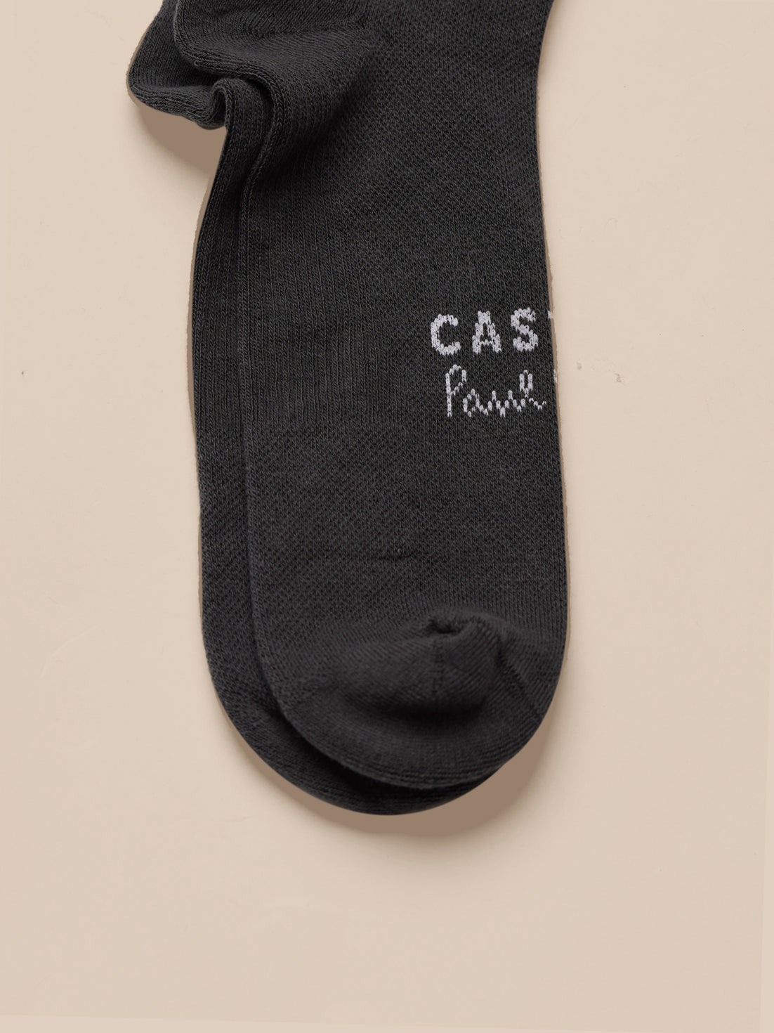 Black sock with 'CASTORE Paul Smith' text on a beige background