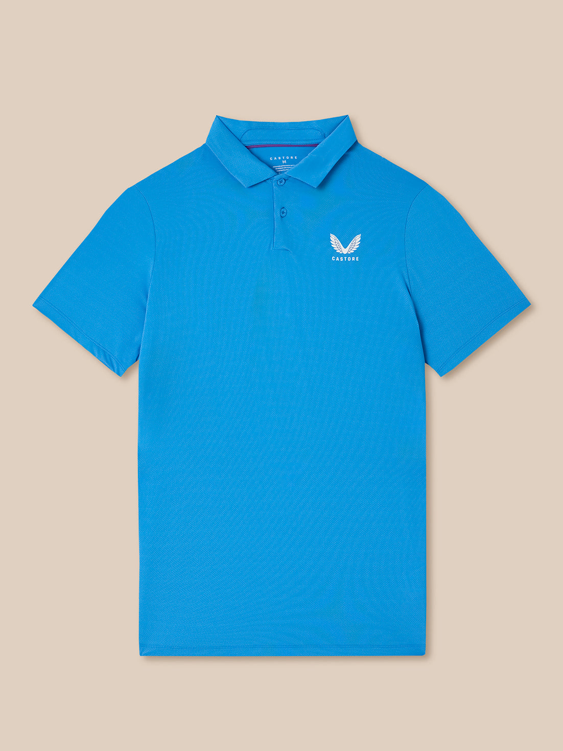 Blue polo shirt with the Castore logo on a beige background