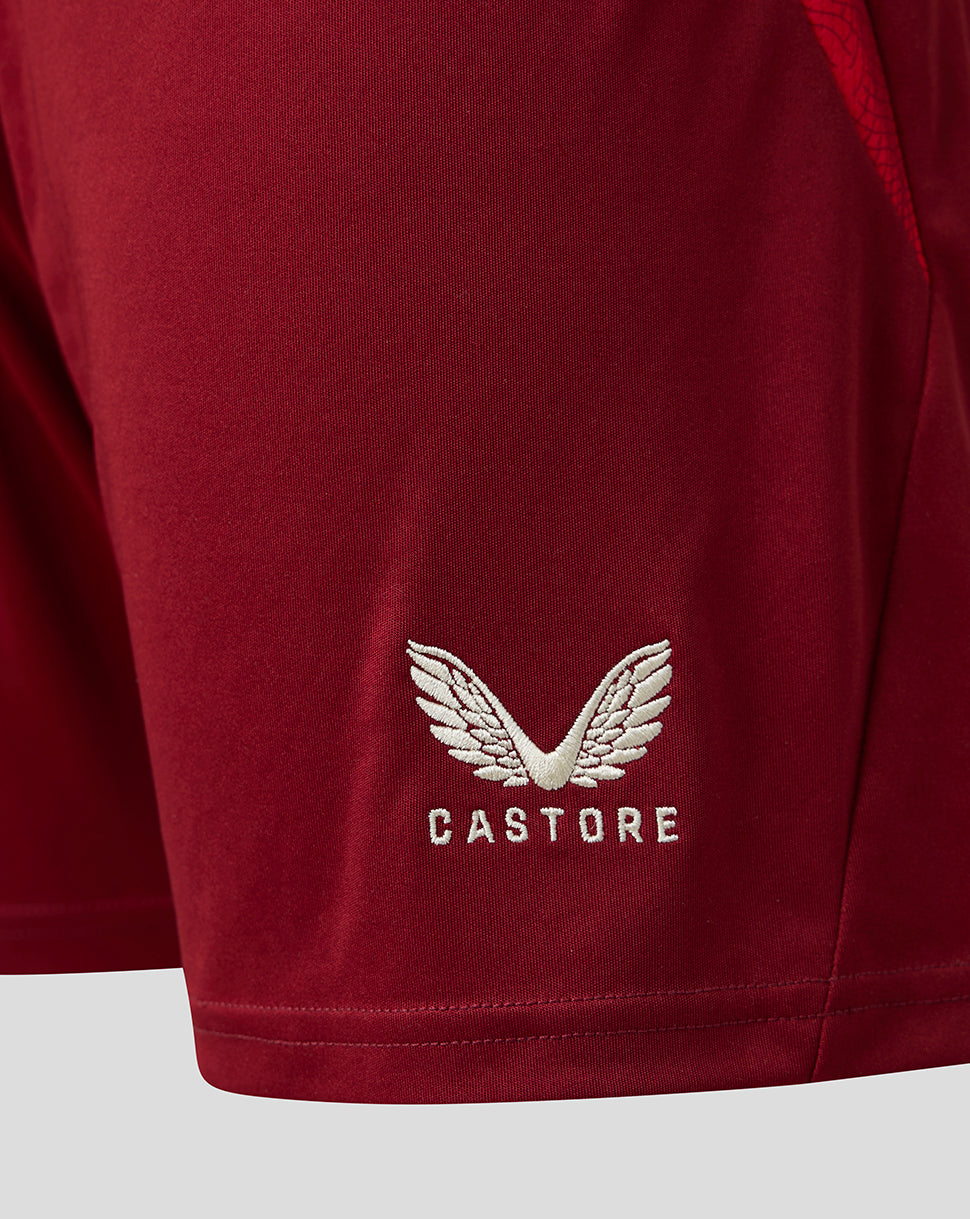 Close-up of a red athletic shorts leg featuring a white embroidered wing logo and the brand name 'CASTORE' on the lower left leg.