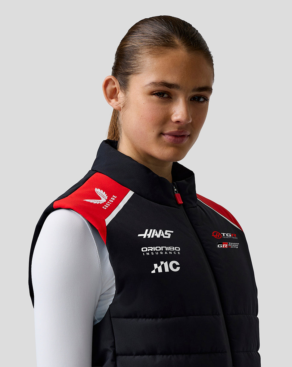 Person wearing a black racing suit with various logos on a gray background