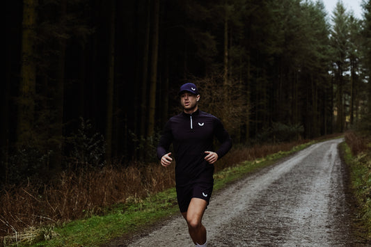Runner wearing a dark athletic outfit jogs along a forest trail
