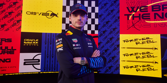 F1 driver in Castore racing gear posed against a colorful sponsor wall featuring Red Bull branding