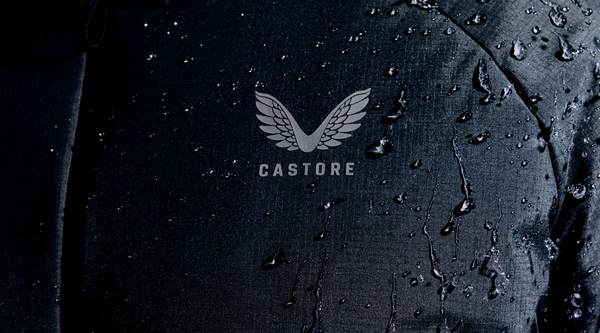Close up of dark Protek fabric with water droplets and the Castore logo.