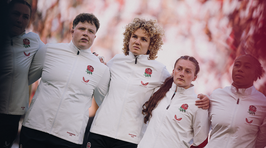Group of athletes in white zip jackets with red rose crest standing with arms around each other