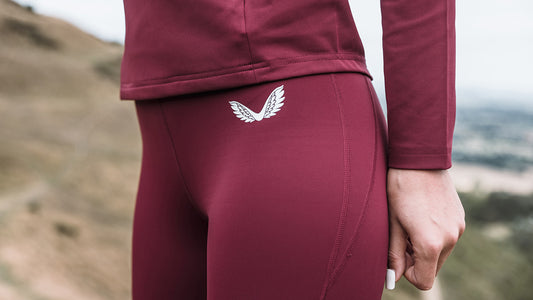 Close up of burgundy leggings with a white wing logo on the back waistband