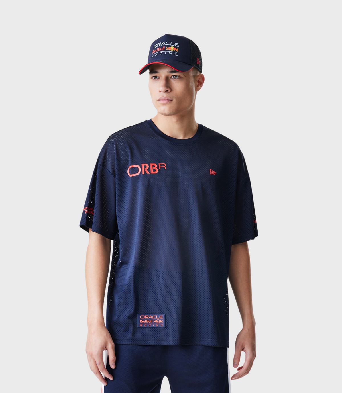 Man wearing a navy mesh T shirt with Oracle Red Bull Racing logo on chest and a navy cap with red brim