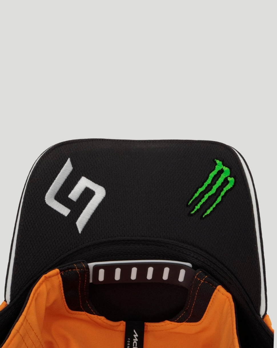 Front close-up of a black McLaren Team Norris cap with a white logo and a green Monster energy emblem, orange interior visible