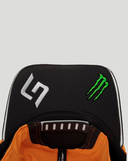 Front close-up of a black McLaren Team Norris cap with a white logo and a green Monster energy emblem, orange interior visible