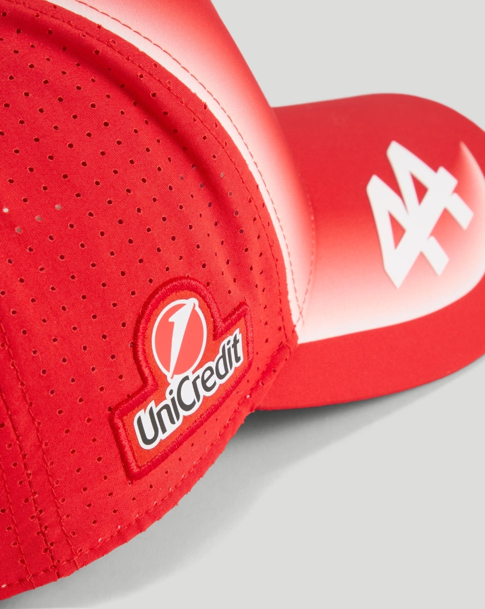 Close up of red Scuderia Ferrari cap with UniCredit patch and white logo on the brim.