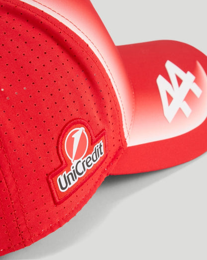 Close up of red Scuderia Ferrari cap with UniCredit patch and white logo on the brim.