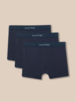 Three pairs of Castore men's boxer briefs in a dark navy blue color, arranged in a staggered stack on a solid beige background.