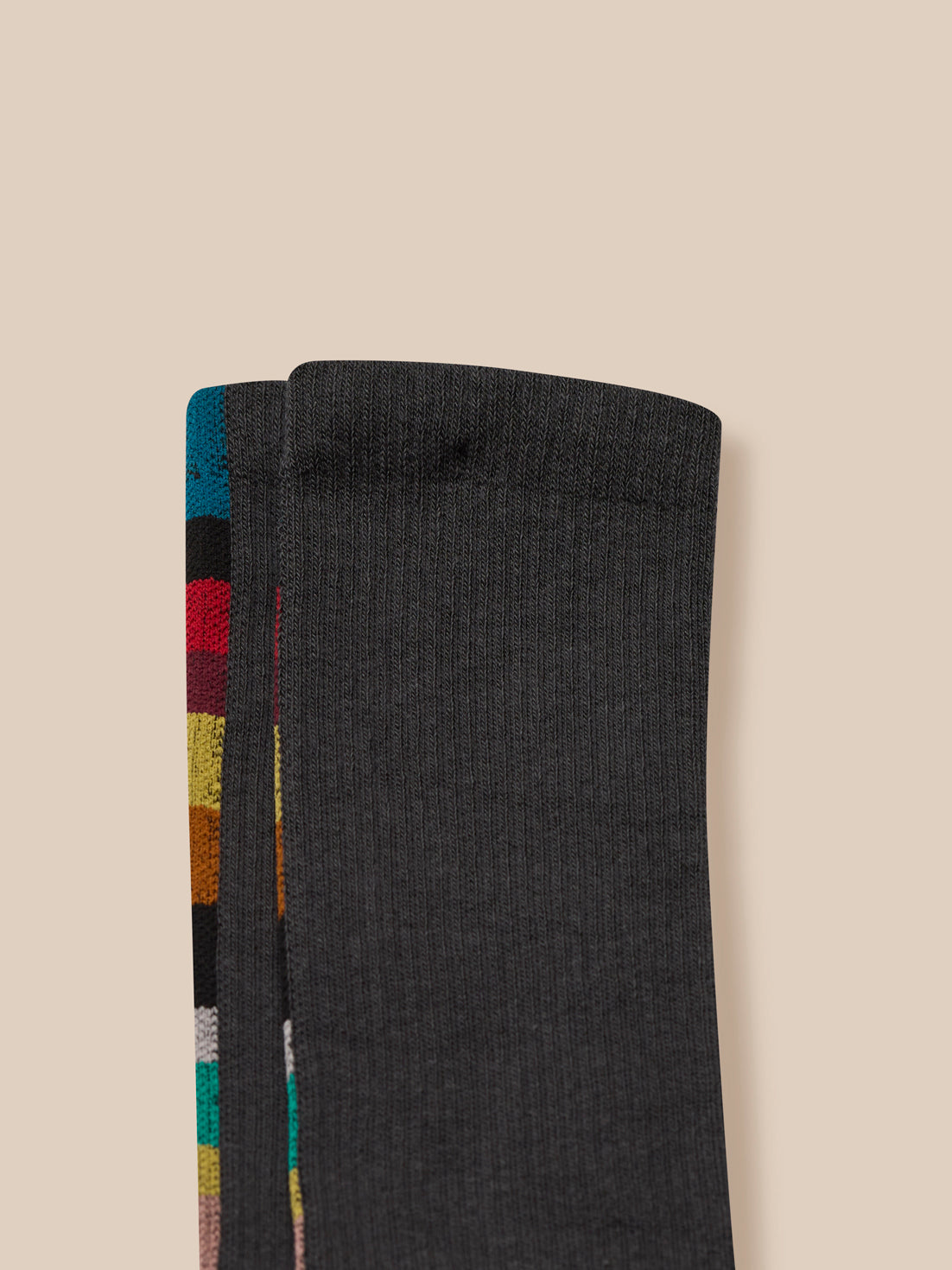 Black sock with colorful striped pattern on a beige background