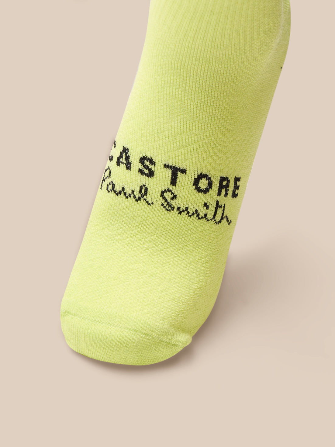 Yellow sock with branding on a beige background