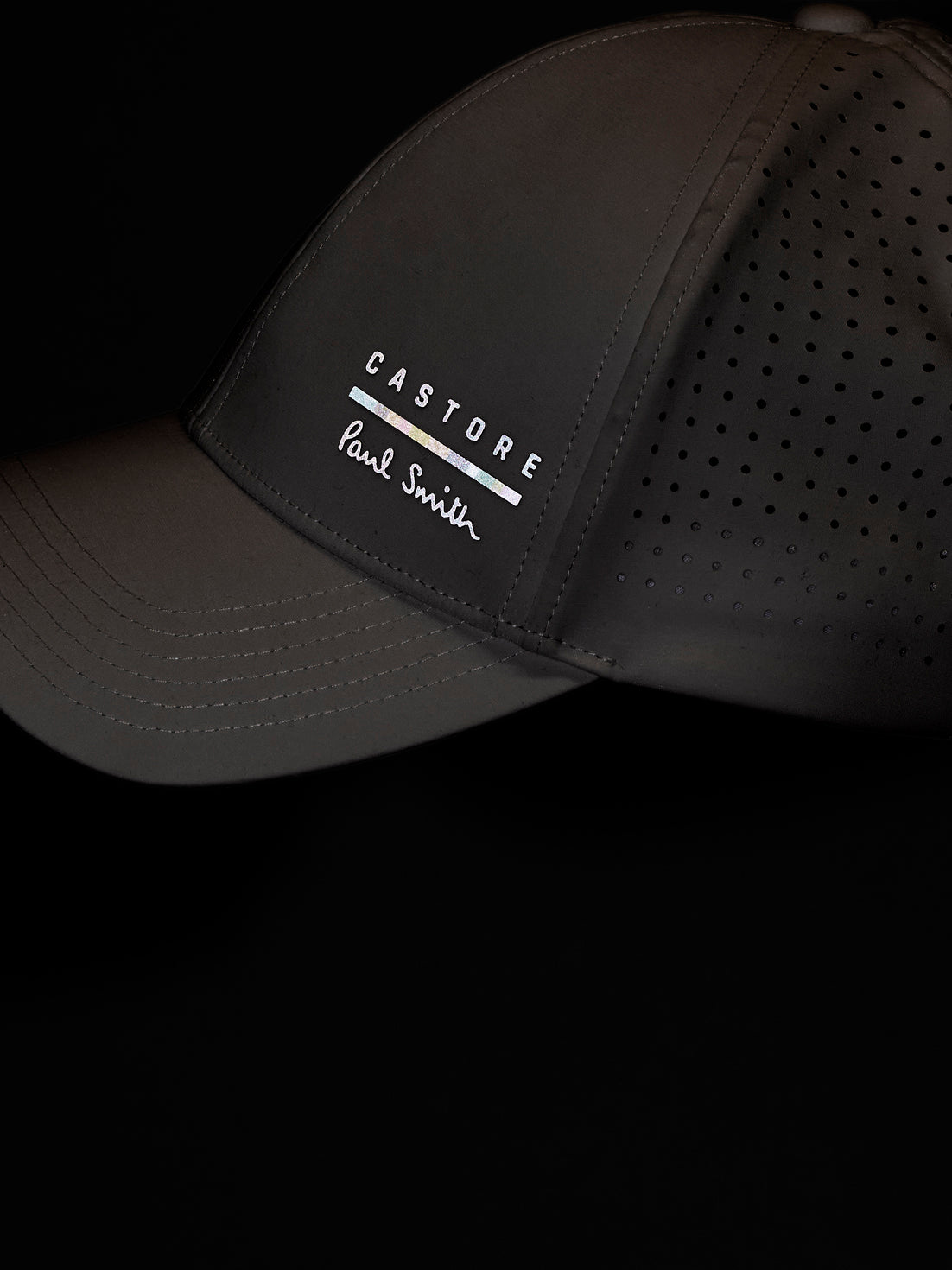White cap with 'Castore' and 'Paul Smith' branding on a black background
