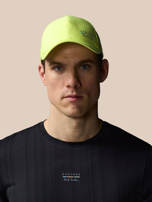 Man wearing a bright yellow cap and black t-shirt with branding on a beige background