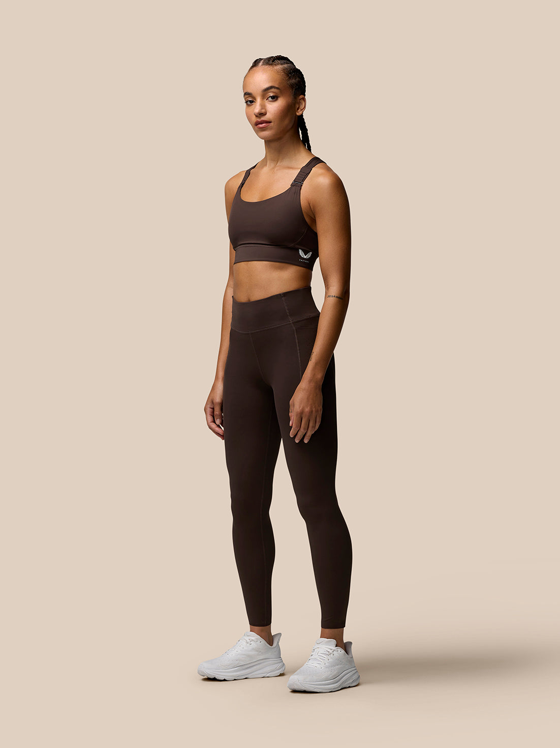 Side view of a model wearing brown Zone Training Sports Bra with racerback and adjustable straps.
