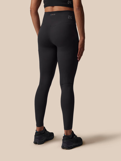 Person wearing black leggings on a beige background