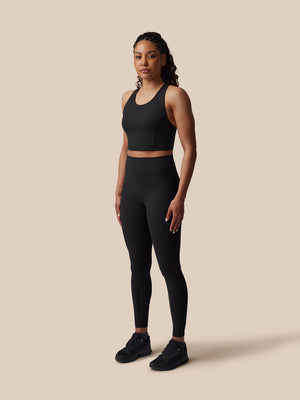 Woman wearing a black athletic outfit on a beige background