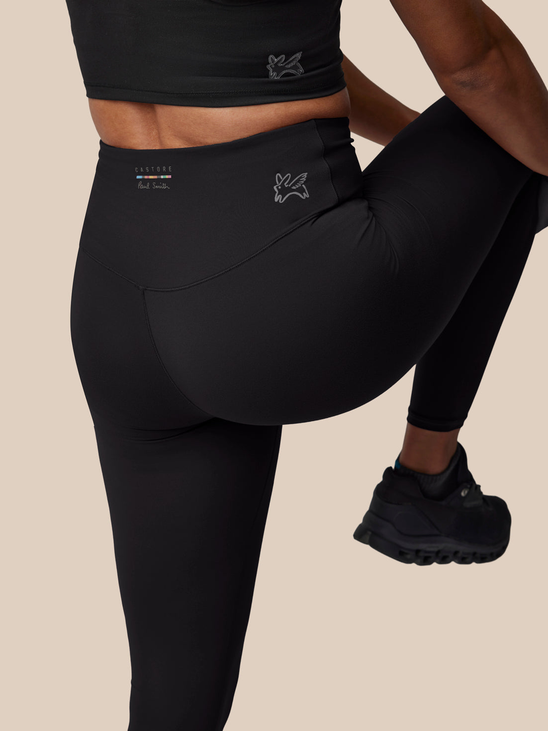 Person wearing black athletic leggings with a beige background