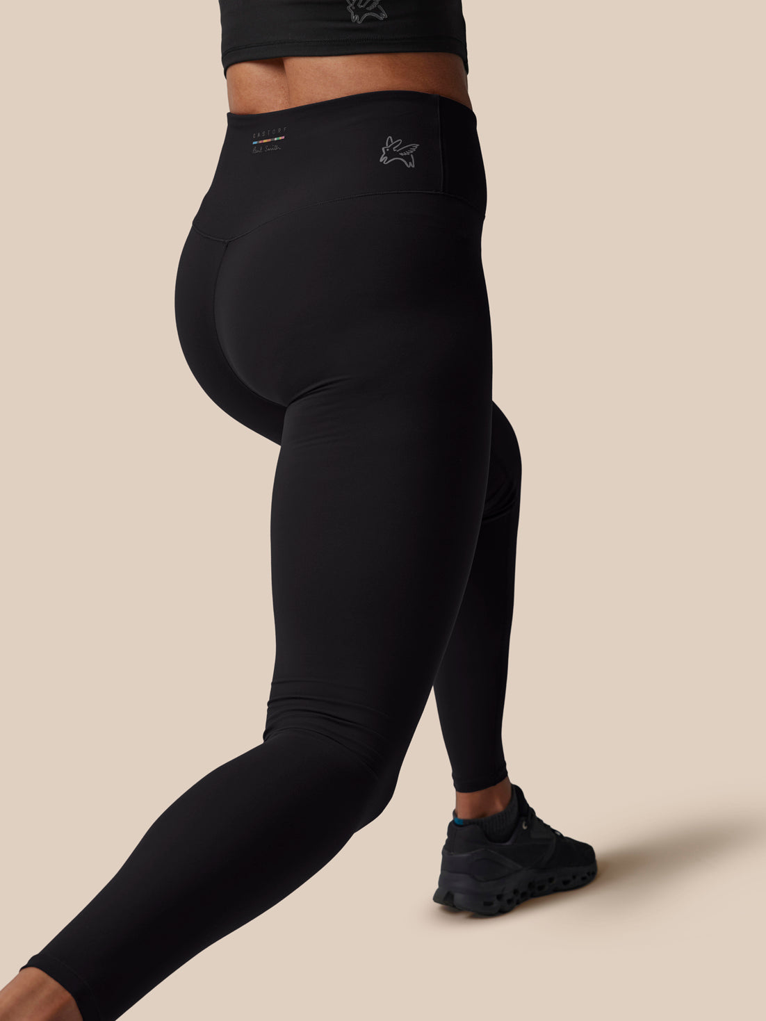 Person wearing black leggings on a beige background