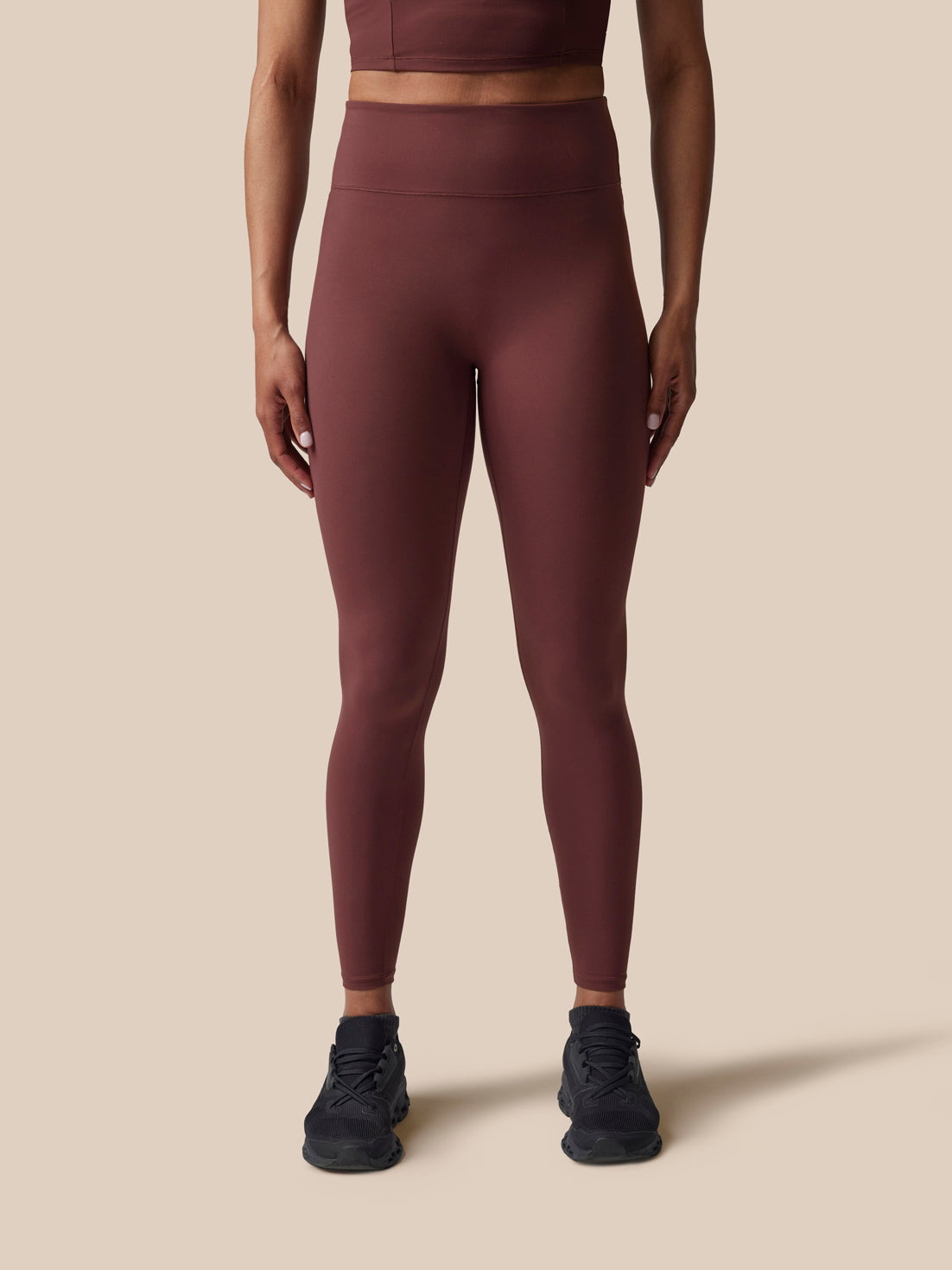 Person wearing maroon leggings on a beige background