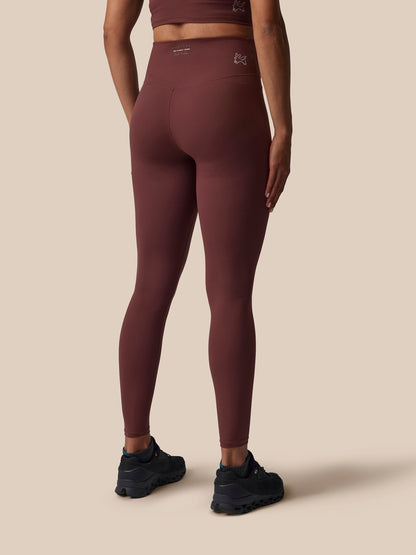 Person wearing maroon leggings on a beige background