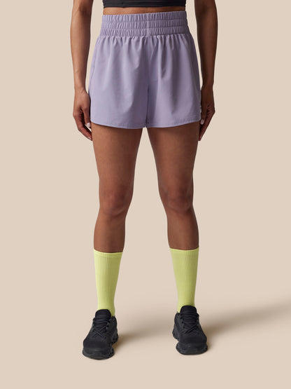 Person wearing light purple shorts and yellow socks on a beige background