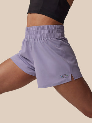 Person wearing light purple athletic shorts on a beige background