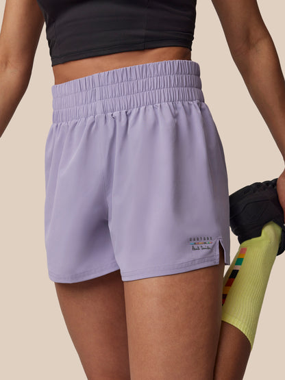 Person wearing light purple athletic shorts on a beige background