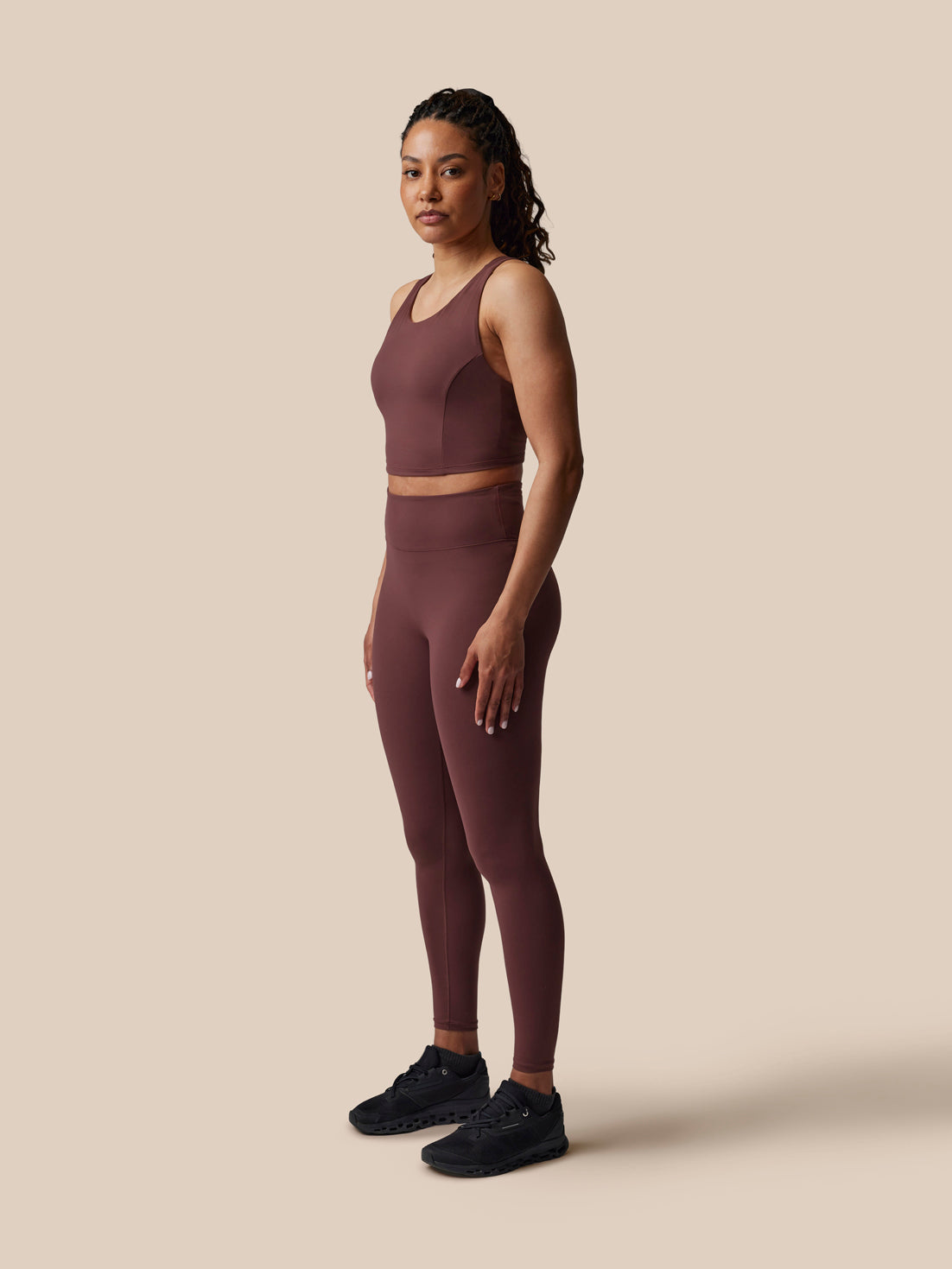 Woman wearing a brown athletic outfit on a beige background
