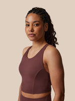 Woman wearing a brown sports bra and leggings against a beige background