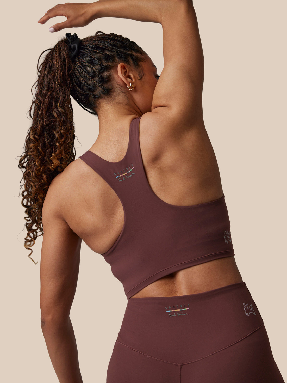 Person wearing a maroon sports bra and leggings on a beige background