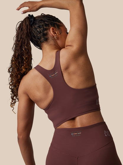 Person wearing a maroon sports bra and leggings on a beige background