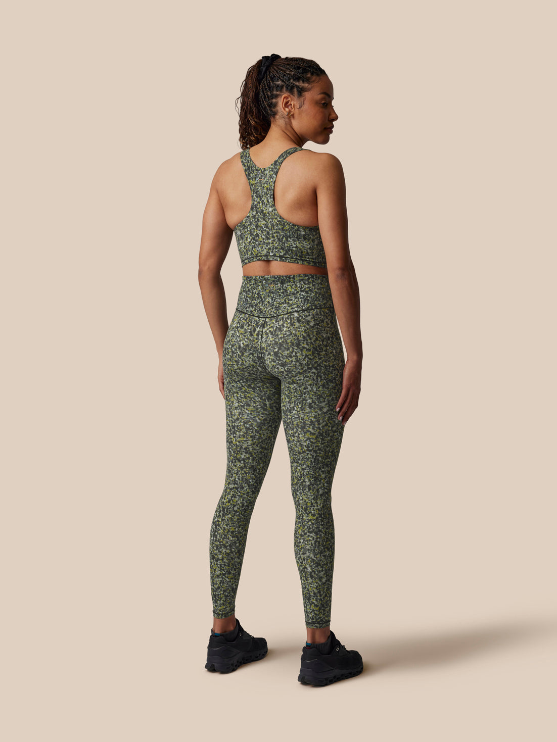 Person wearing a green patterned athletic outfit on a beige background