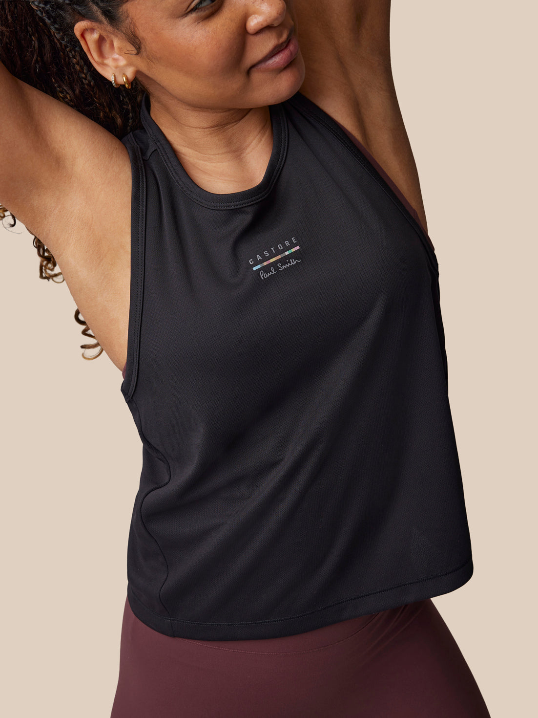 Woman wearing a black tank top with a brand logo on a beige background