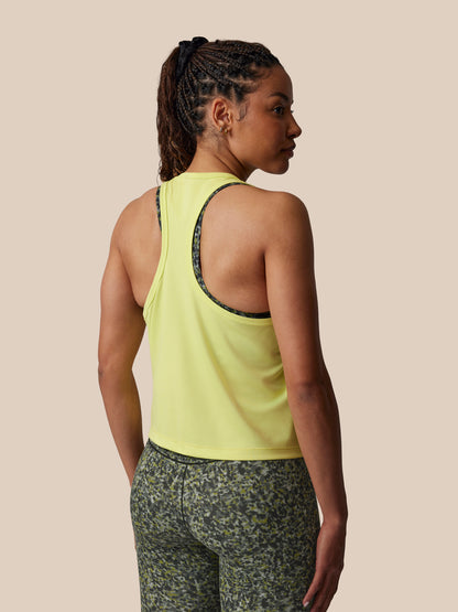 Woman wearing a yellow tank top and patterned leggings on a beige background