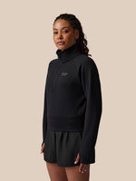 Woman wearing a black outfit with a logo on a beige background