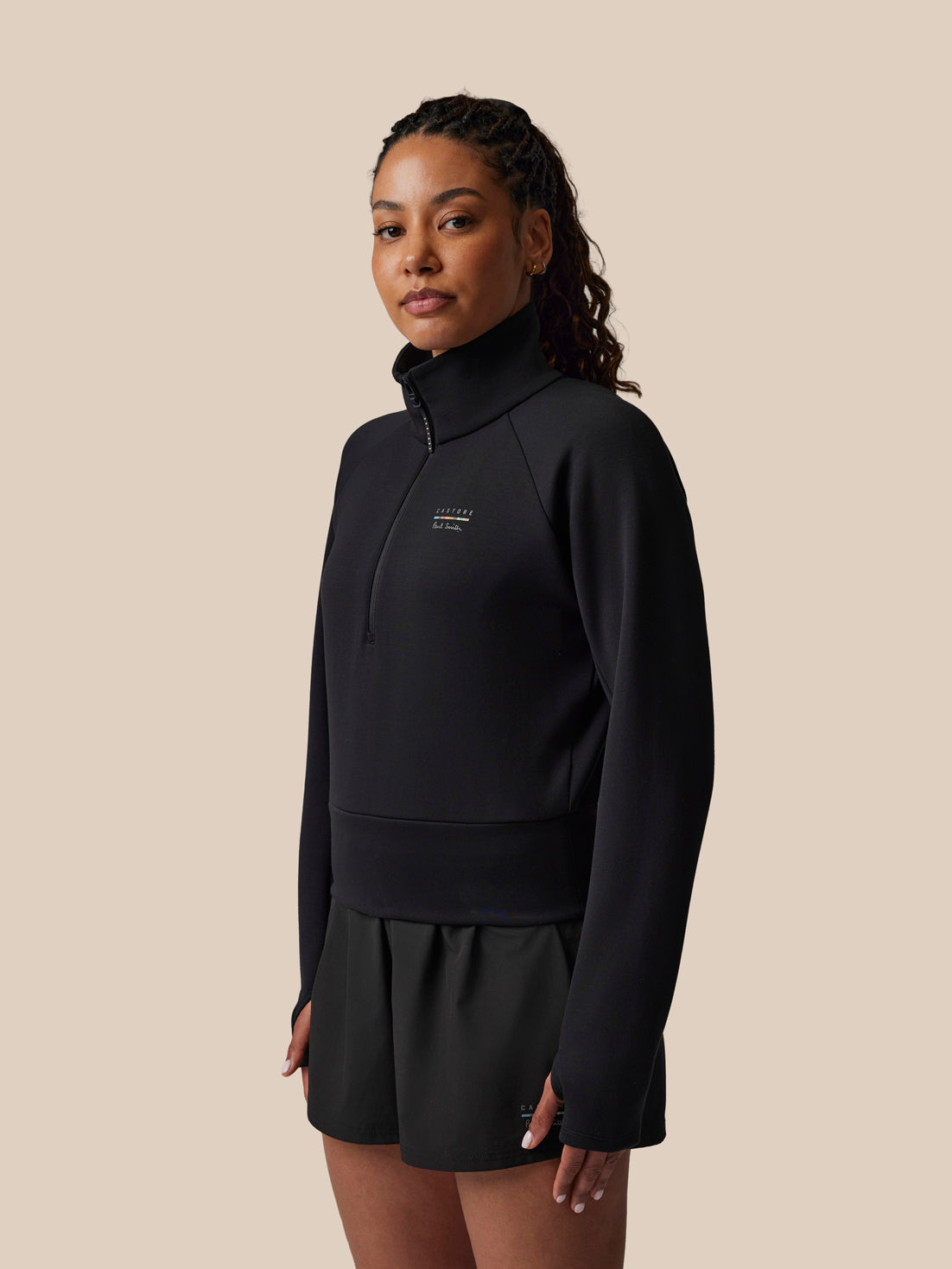 Woman wearing a black outfit with a logo on a beige background