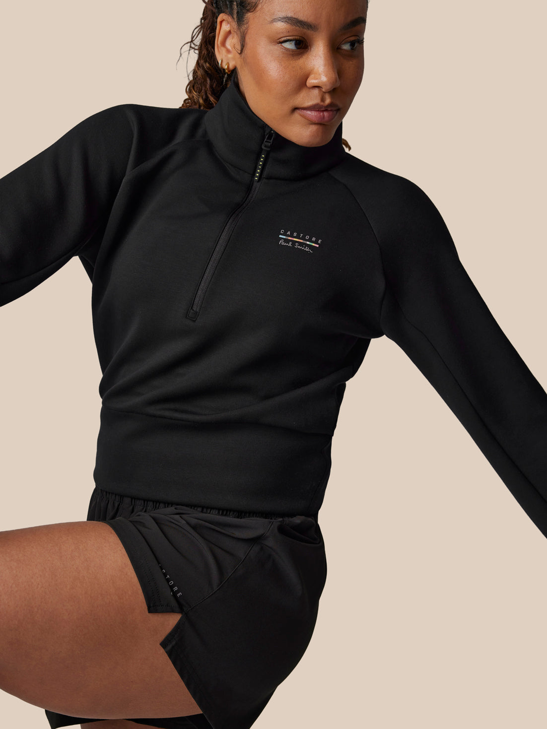Person wearing a black athletic outfit with a visible brand logo on a beige background