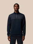 Male model wearing navy Castore Flex Lifestyle quarter-zip top with zip pockets and left chest branding.