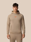Front view of a male model wearing clay Adapt Fleece Hoodie with open front pocket high build collar and subtle branding.