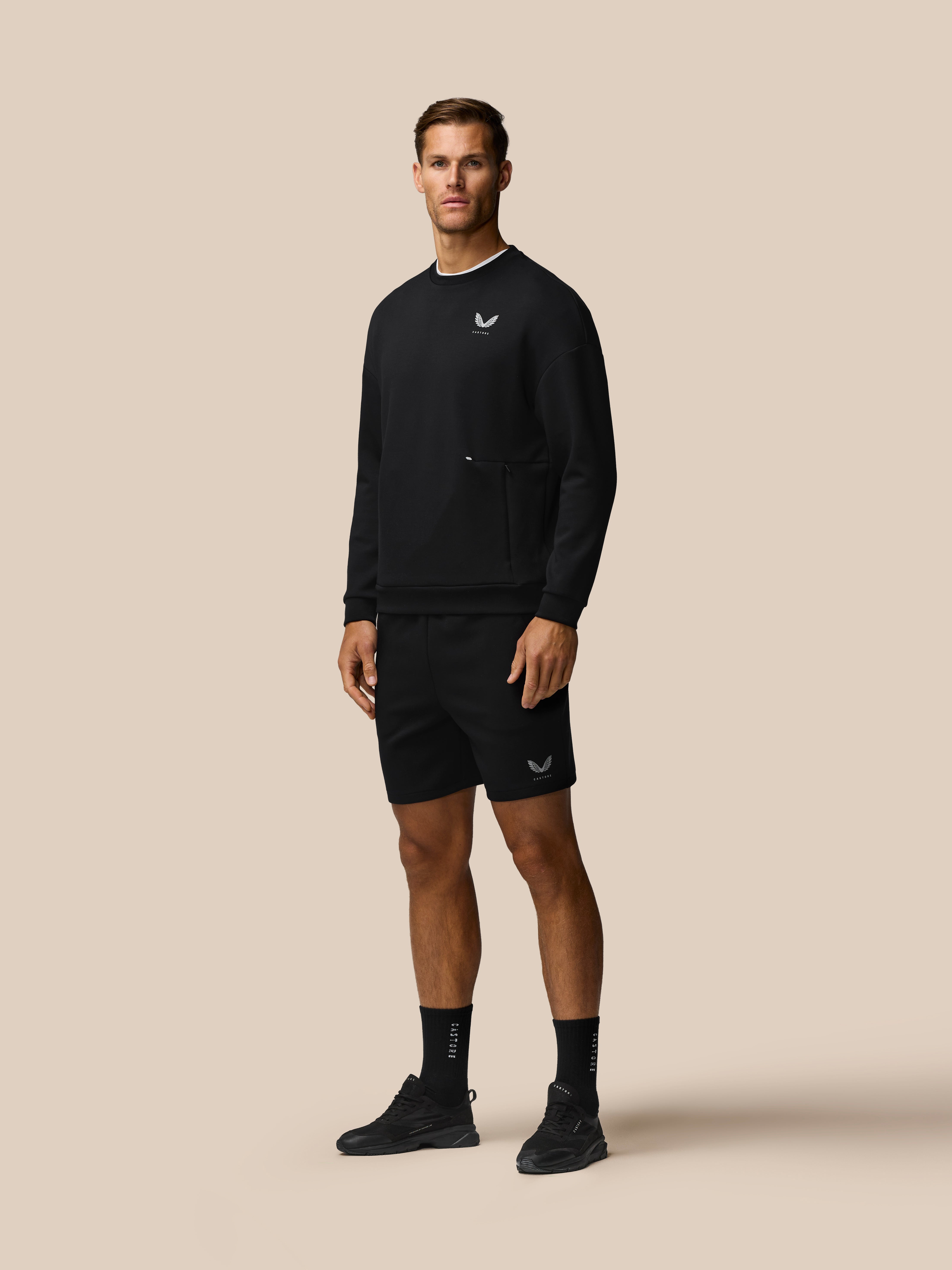 Model wearing black Travel Lifestyle Shorts with concealed zip pockets and Castore logo on leg