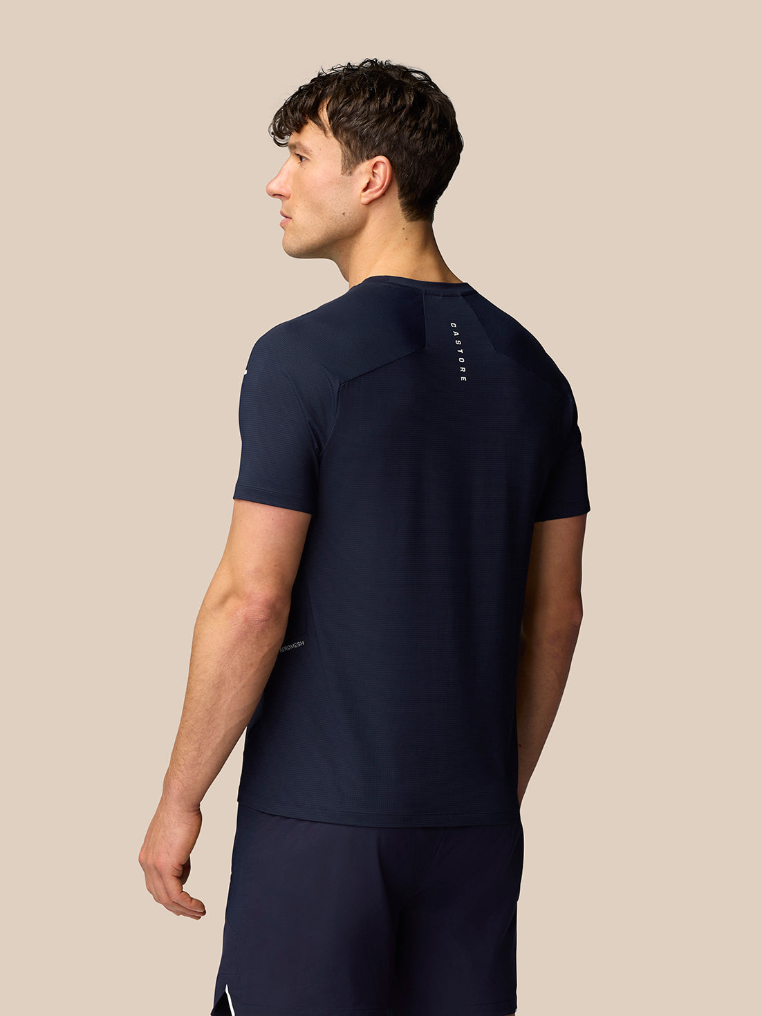 Back view of male model in navy Apex Training T-Shirt with vertical Castore branding at the upper back.