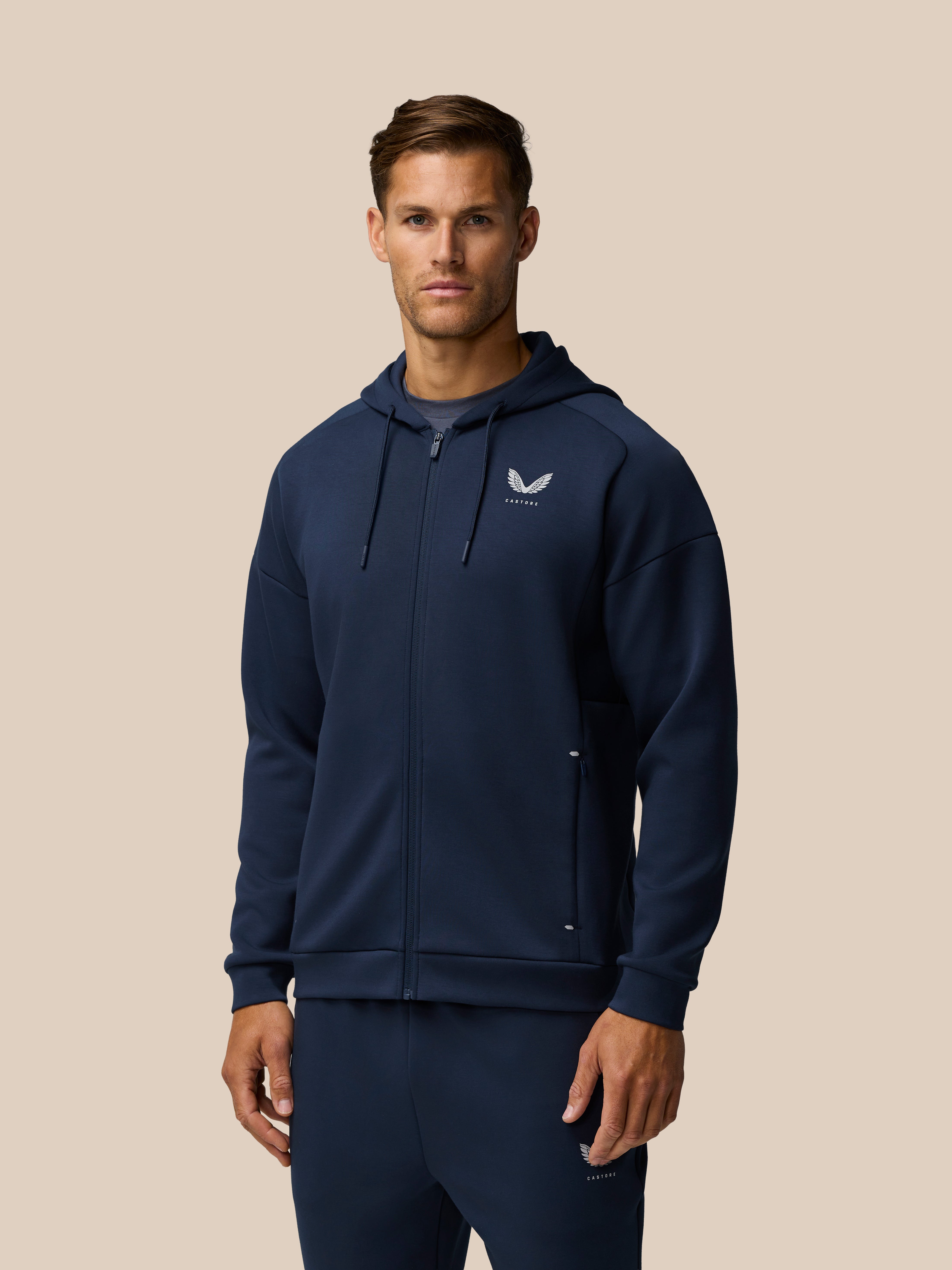 Model wearing navy Travel Lifestyle Zip Hoodie with left chest logo and zip closure