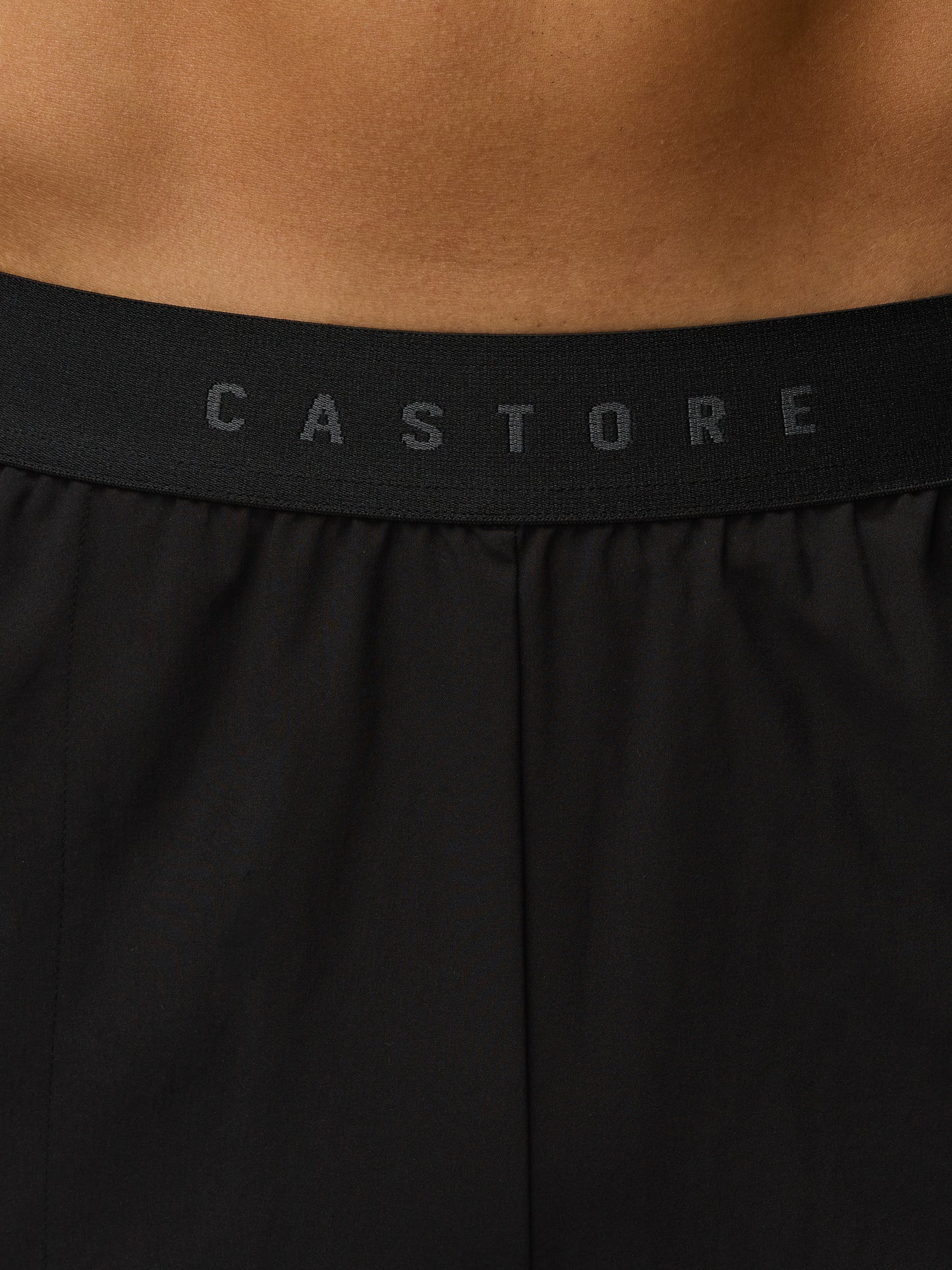 Black athletic shorts with 'Castore' branding on a brown background