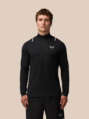 Front view of a man in a black Apex Training quarter zip top with reflective shoulder accents