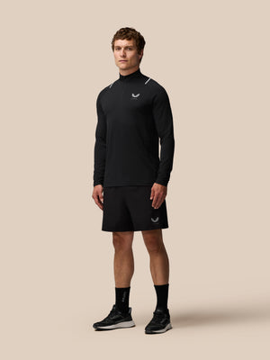 Man wearing black Apex Training quarter zip top with reflective shoulder accents and Castore logo on chest