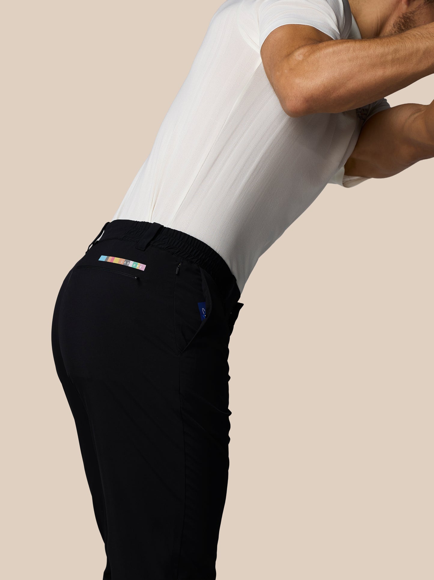Person wearing black pants with a visible brand logo on a beige background