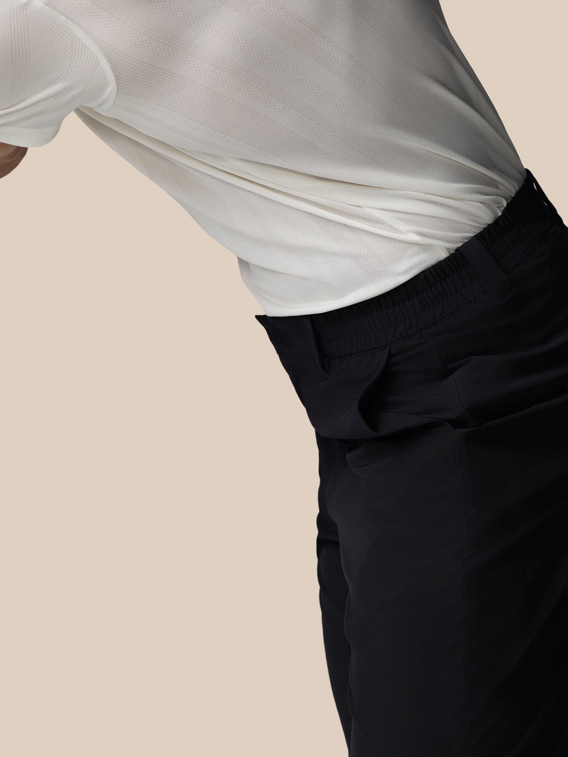 Person wearing a white shirt and black pants on a beige background