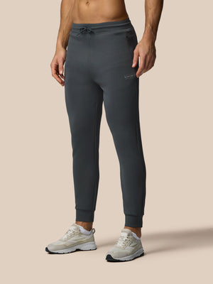 Person wearing dark gray jogger pants on a beige background